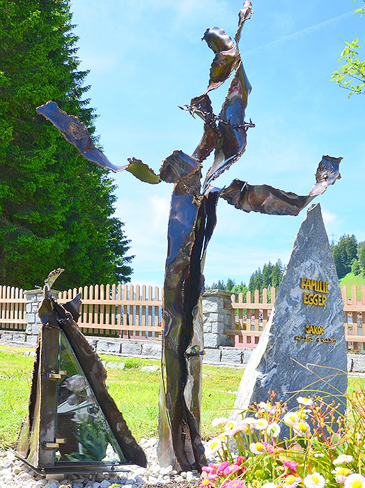 Gerissene Bronzestäbe zur Kreuz-Skulptur gebogen